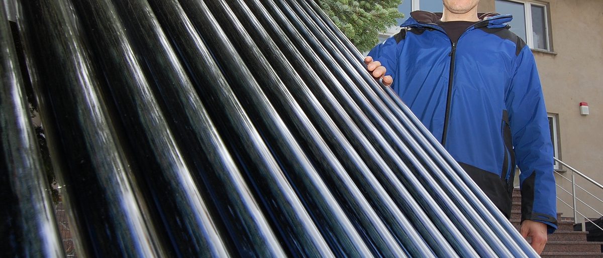 Detlef Fesser, Installateur- und Heizungsbauermeister bei der Renoc Wärme GmbH steht vor einem Solarkollektor, der zur Warmwasseraufbereitung genutzt wird. 