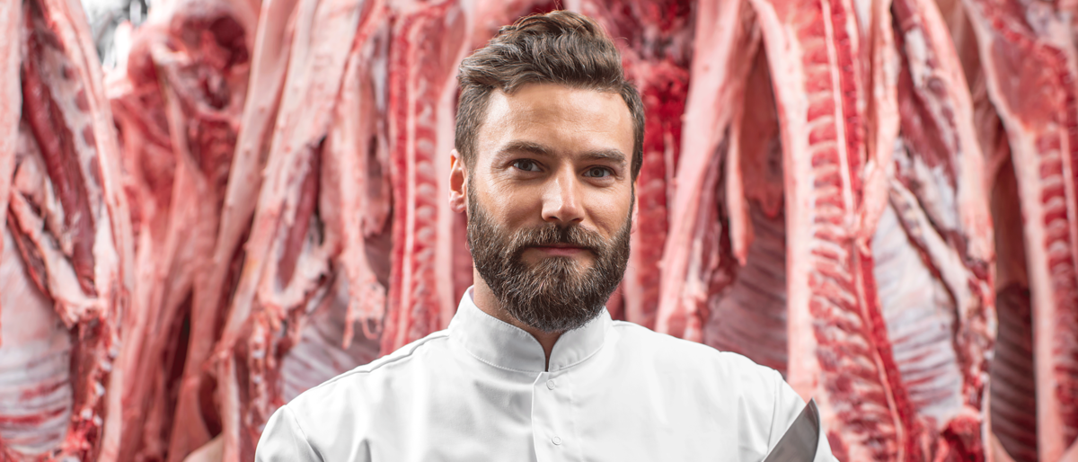 Fleischer,Bart,Model,Fleischerei,Mann steht vor Fleisch,Handwerk,Fleischerei,Metzger,Fleischer Meisterschule