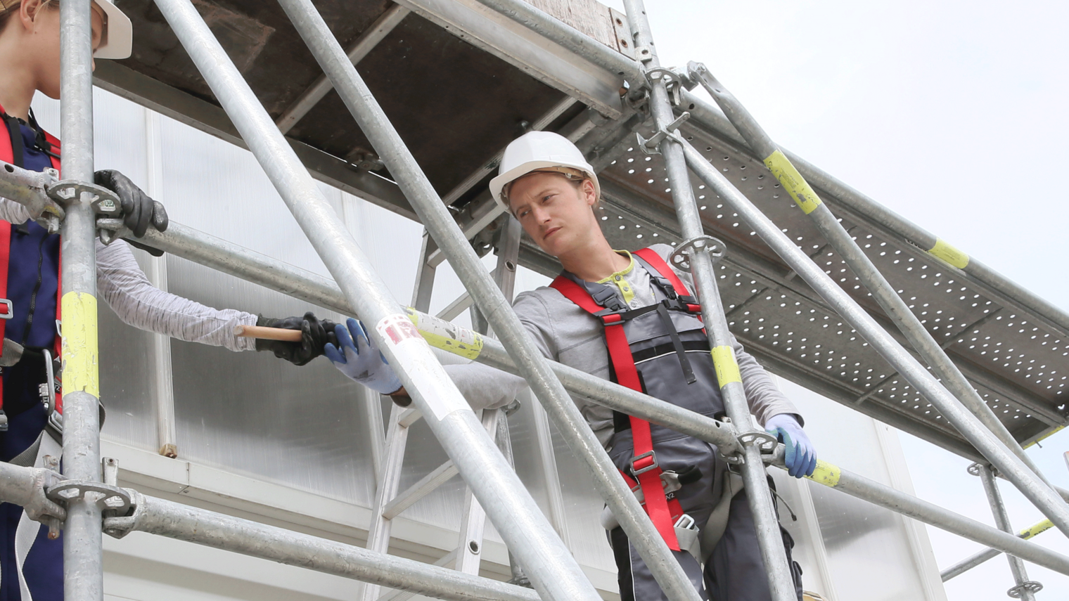 Gerüstbua,Gerüstbau Ausbildung,Gerüstbau Meisterschule,Handwerk,Gerüstbauer,Gerüstbauerin,Frau Gerüstbau,Mehrere Personen bauen ein Gerüst