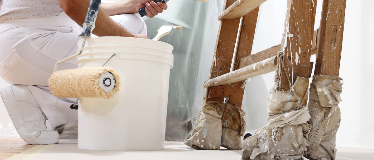Maler,Lackierer,Maler und Lackierer,Malermeister,Maler und Lackierer Meisterschule,Handwerk,Meisterschule,Malerhandwerk,meisterausbildung Maler und Lackierer,Maler hockt vor einer Leiter und streicht eine Wand