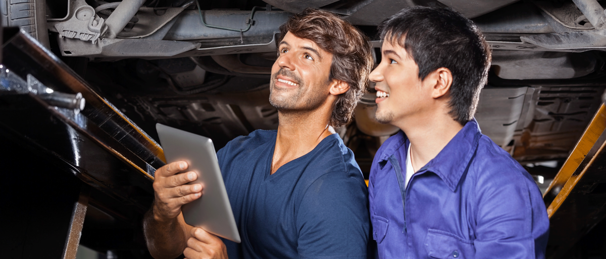 Ausbilder und Lehrling stehen unter einem Auto,Ausbildung,Lehrstelle,Kfz,Kfz Mechatroniker