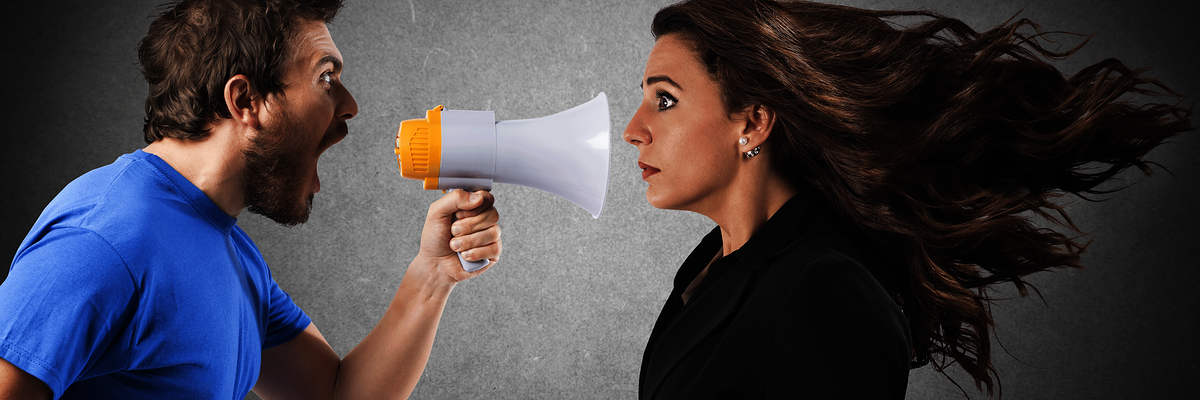 Mann schreit Frau mit einen Megaphone an,Konflikt,Konfliktmanagement